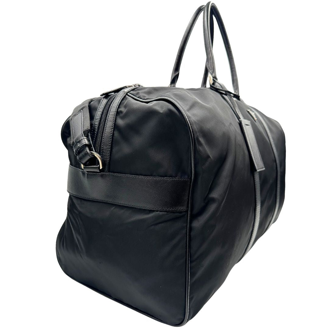 lato  Borsone Prada in nylon nero con finiture in pelle tono su tono e parti metalliche argentate; munito di doppi manici stondati e un manico singolo in tessuto, indossabile a spalla o mano. Completo di dustbag e tag porta address, di lusso, originale, ottime condizioni, usata. 