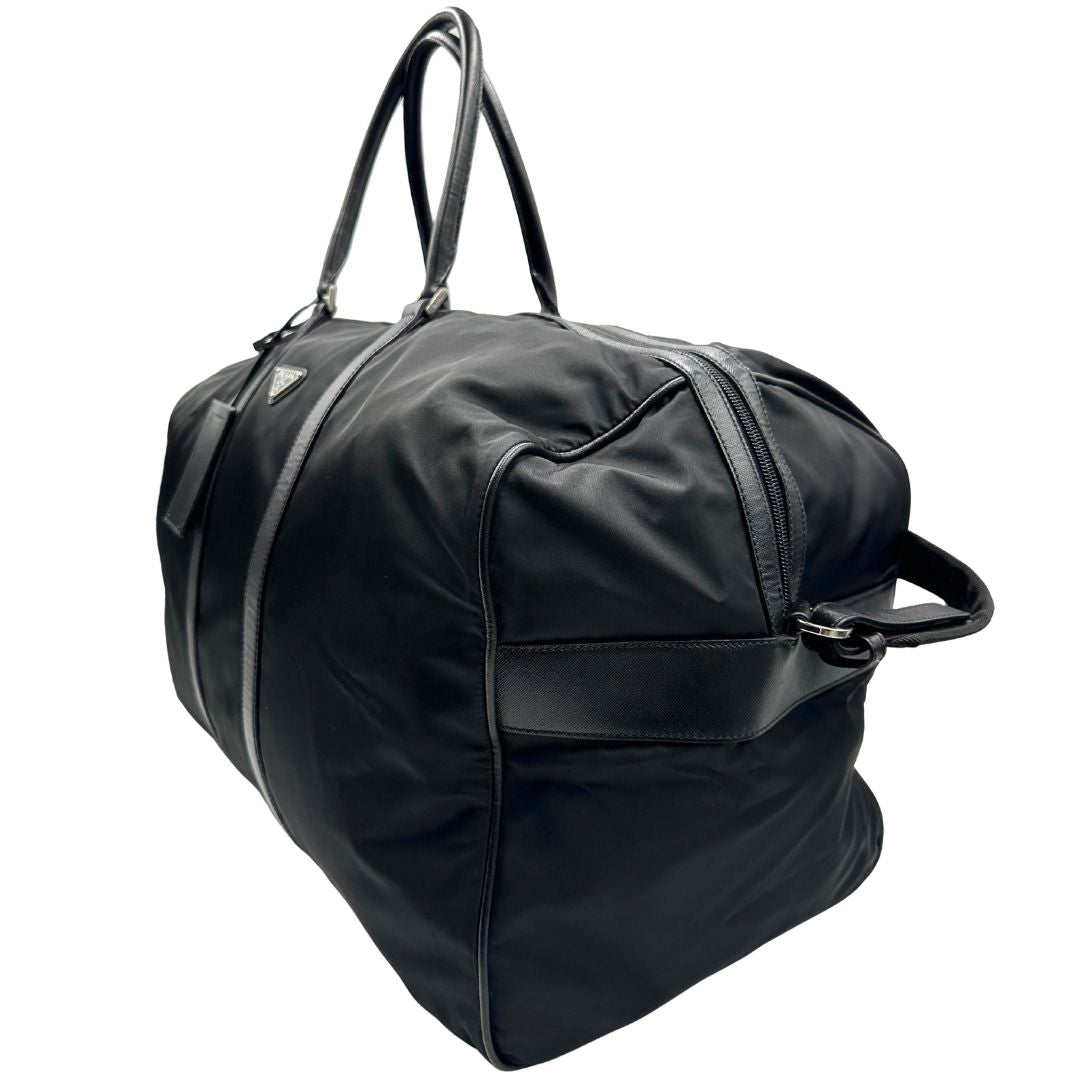 lato  Borsone Prada in nylon nero con finiture in pelle tono su tono e parti metalliche argentate; munito di doppi manici stondati e un manico singolo in tessuto, indossabile a spalla o mano. Completo di dustbag e tag porta address, di lusso, originale, ottime condizioni, usata. 