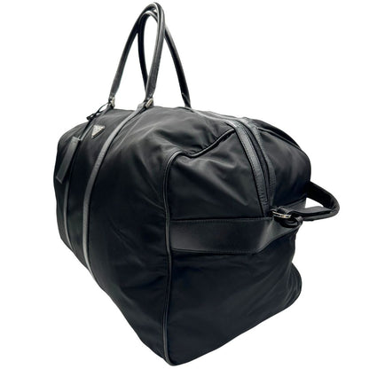 lato  Borsone Prada in nylon nero con finiture in pelle tono su tono e parti metalliche argentate; munito di doppi manici stondati e un manico singolo in tessuto, indossabile a spalla o mano. Completo di dustbag e tag porta address, di lusso, originale, ottime condizioni, usata. 