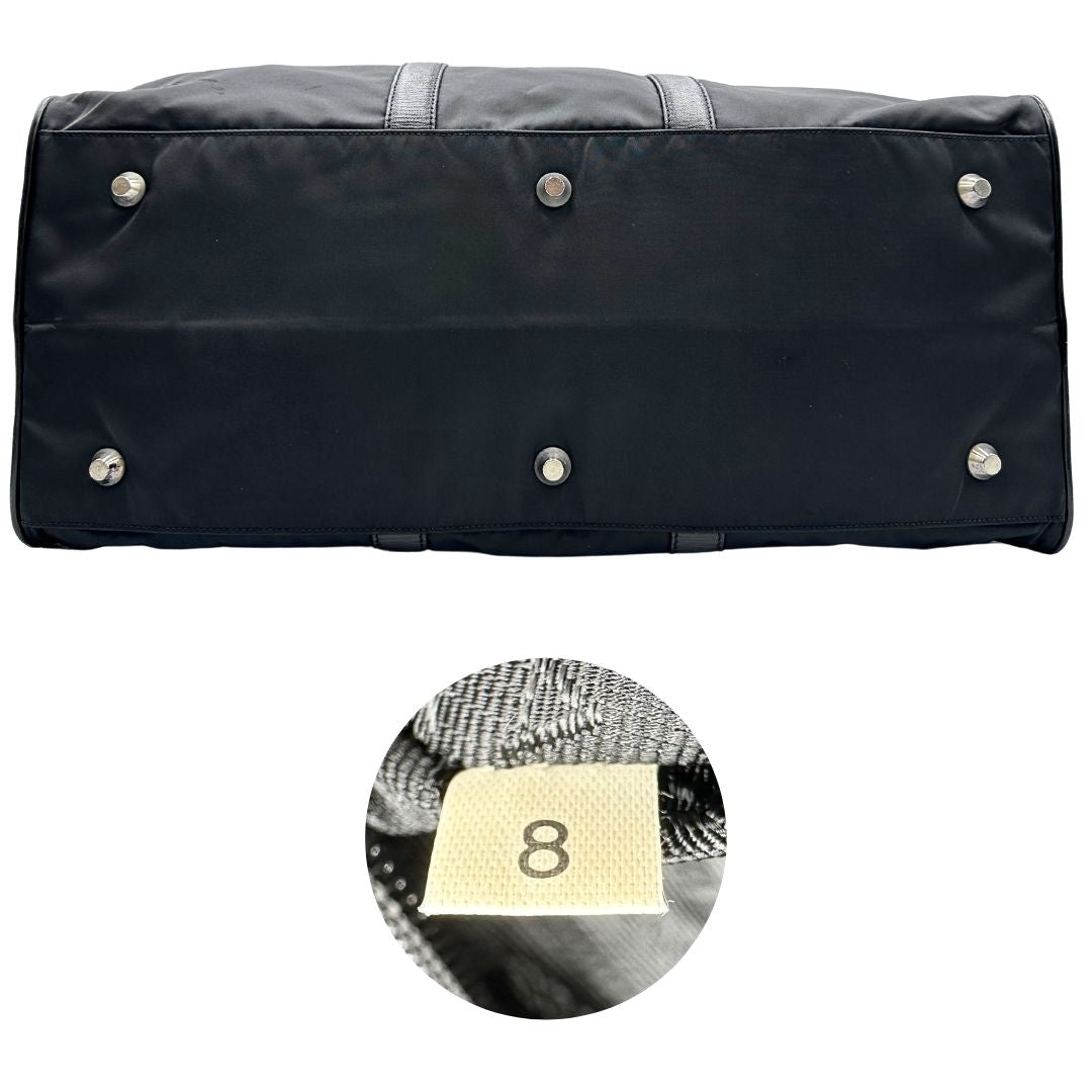 Base e codice di un borsone Prada in nylon nero con finiture in pelle Saffiano tono su tono e parti metalliche argentate. Completo di dustbag, tag porta address e lucchetto. Indossabile a mano.