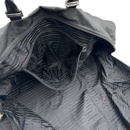 Interno di un borsone Prada in nylon nero con finiture in pelle Saffiano tono su tono e parti metalliche argentate. Completo di dustbag, tag porta address e lucchetto. Indossabile a mano.