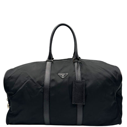 Front di un borsone Prada in nylon nero con finiture in pelle Saffiano tono su tono e parti metalliche argentate. Completo di dustbag, tag porta address e lucchetto. Indossabile a mano.