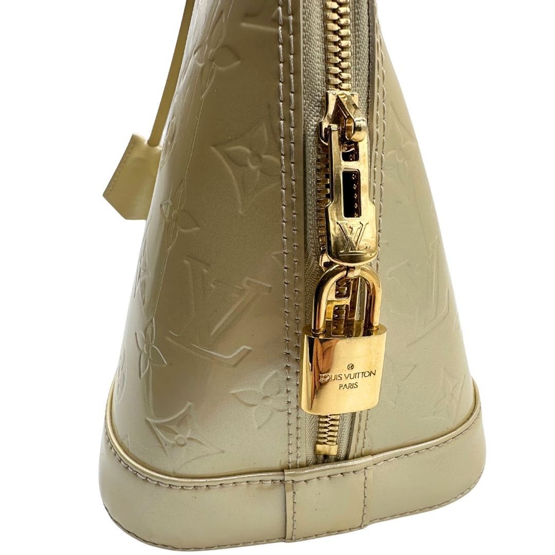 Parti metalliche di una borsa Alma PM Louis Vuitton in pelle Vernis color noisette con parti metalliche dorate e doppi manici stondati; da portare a mano. Completa di lucchetto e chiavi. Indossabile a mano.