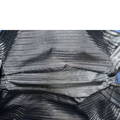 Interno di una borsa Prada in pelle bluette con parti metalliche dorate; munita di un accessorio porta address, doppi manici stondati e una tracolla amovibile e regolabile. Completa di dustbag e card d'autenticità. Indossabile a mano oppure a tracolla.