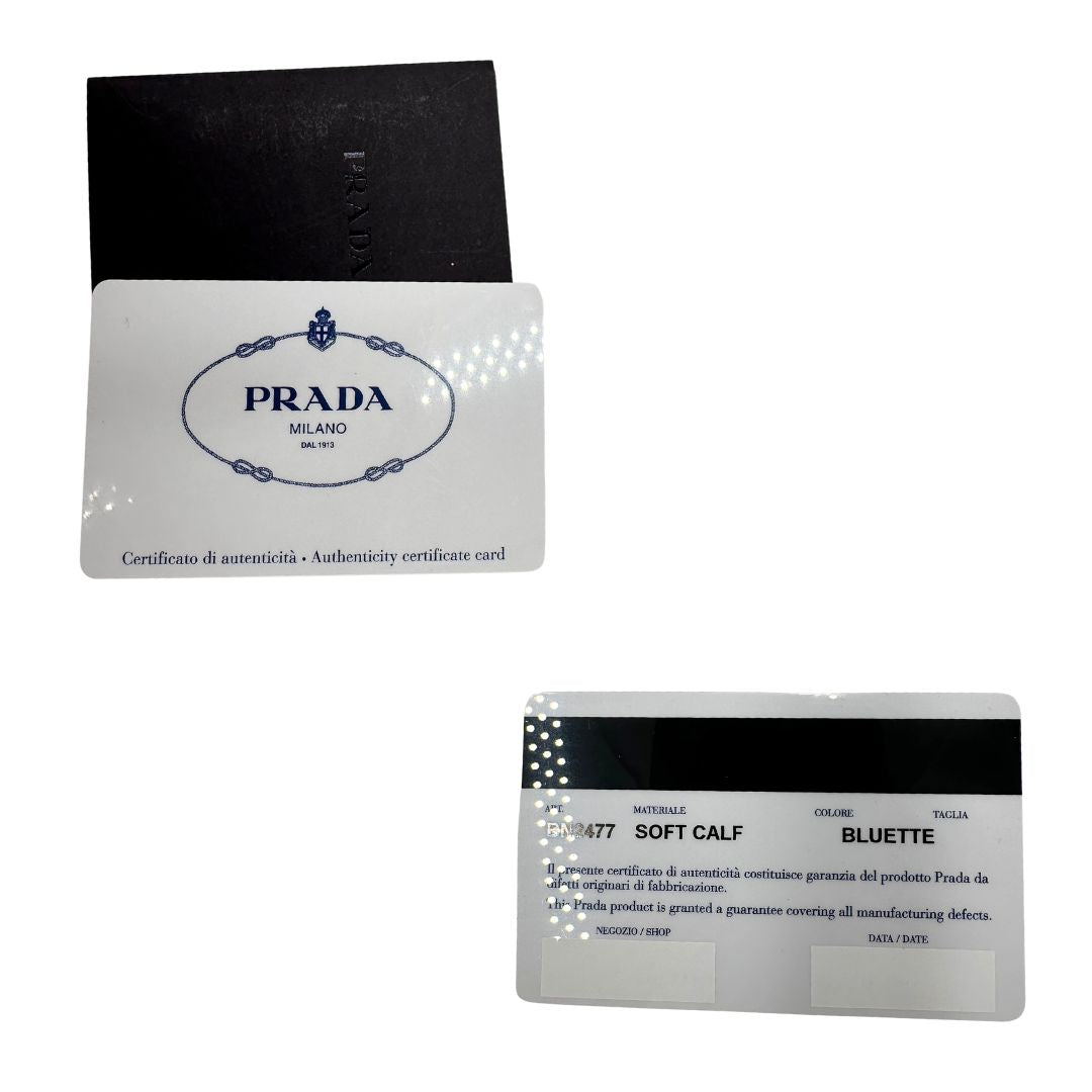 Card di una borsa Prada in pelle bluette con parti metalliche dorate; munita di un accessorio porta address, doppi manici stondati e una tracolla amovibile e regolabile. Completa di dustbag e card d'autenticità. Indossabile a mano oppure a tracolla.