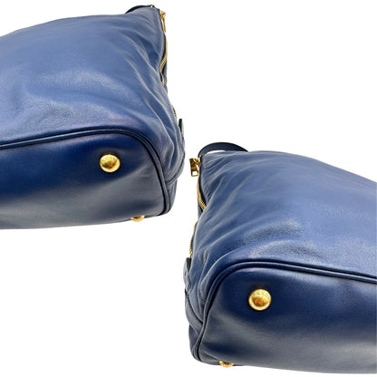 Angoli di una borsa Prada in pelle bluette con parti metalliche dorate; munita di un accessorio porta address, doppi manici stondati e una tracolla amovibile e regolabile. Completa di dustbag e card d'autenticità. Indossabile a mano oppure a tracolla.