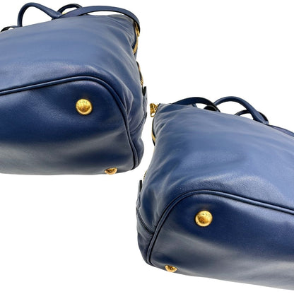 Angoli di una borsa Prada in pelle bluette con parti metalliche dorate; munita di un accessorio porta address, doppi manici stondati e una tracolla amovibile e regolabile. Completa di dustbag e card d'autenticità. Indossabile a mano oppure a tracolla.