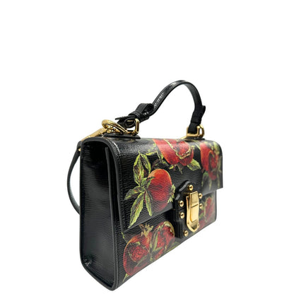 Laterale sinistro di una borsa D&G in pelle nera con stampa melograni e parti metalliche dorate; munita di un manico rigido fisso e una tracolla in pelle regolabile ed amovibile. Completa di dustbag.
