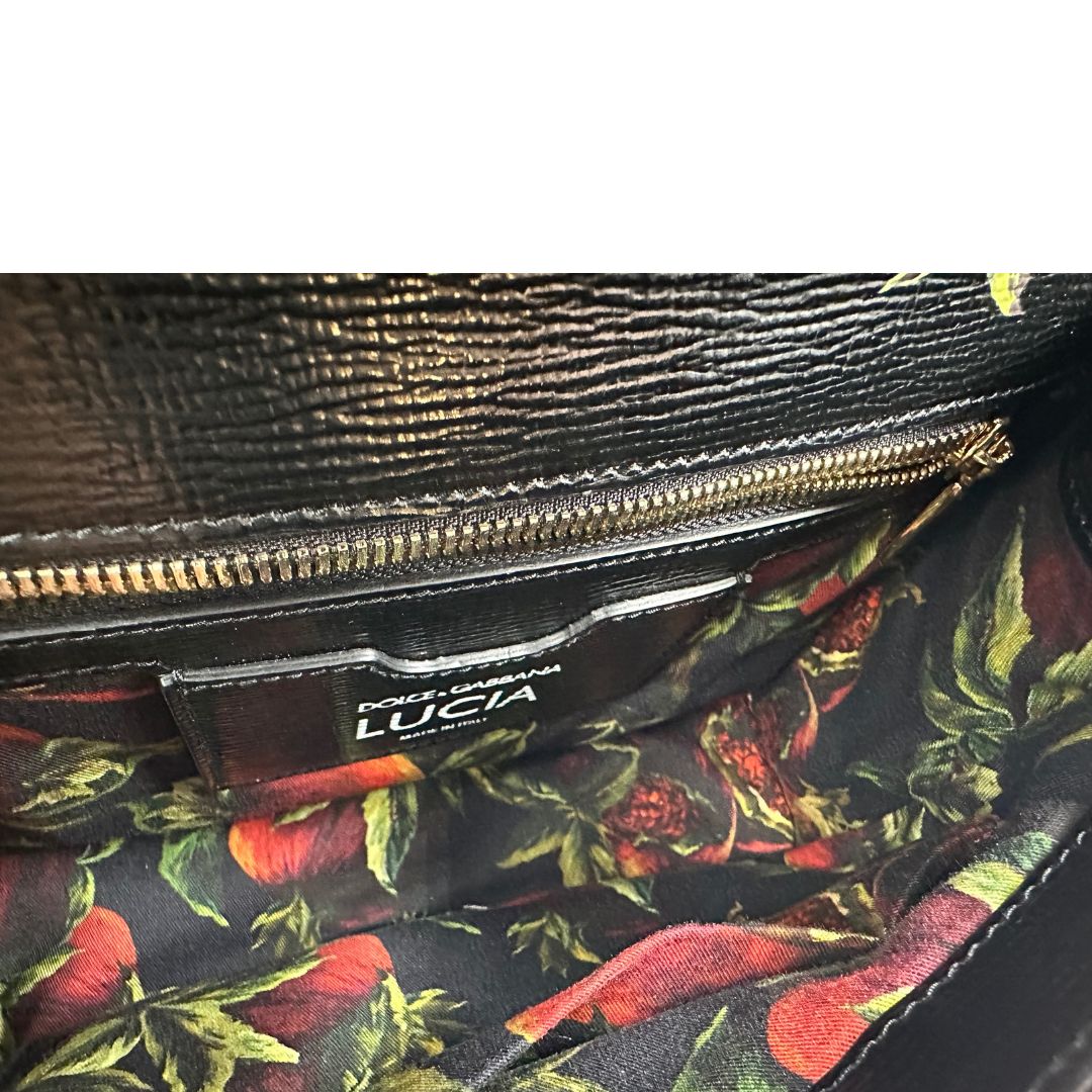Interno di una borsa D&G in pelle nera con stampa melograni e parti metalliche dorate; munita di un manico rigido fisso e una tracolla in pelle regolabile ed amovibile. Completa di dustbag.