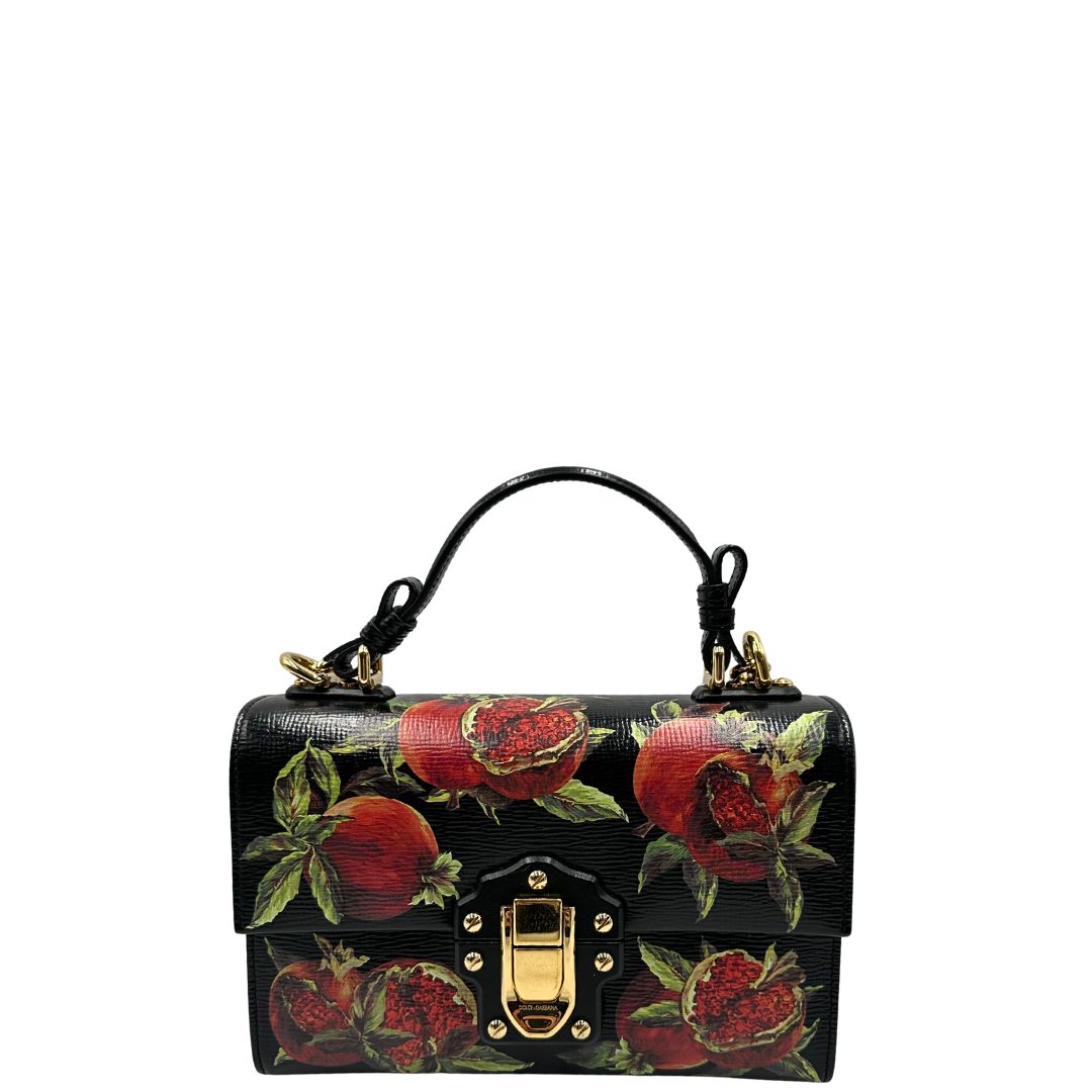 Front di una borsa D&G in pelle nera con stampa melograni e parti metalliche dorate; munita di un manico rigido fisso e una tracolla in pelle regolabile ed amovibile. Completa di dustbag.