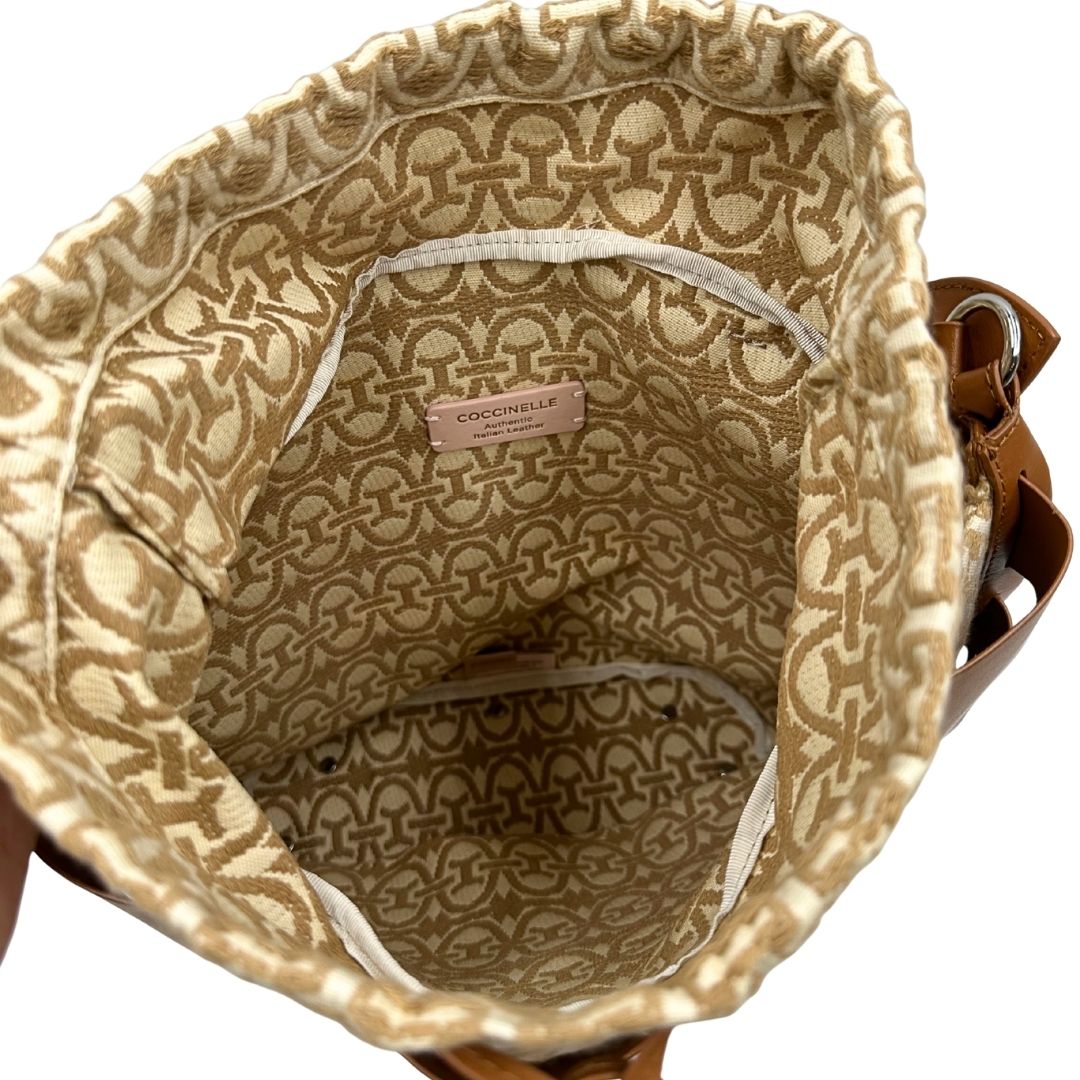 Interno di una borsa Coccinelle in pelle color cammello con parti metalliche argentate e interno in tessuto logato; munita di un manico singolo leggermente regolabile. Indossabile a spalla.