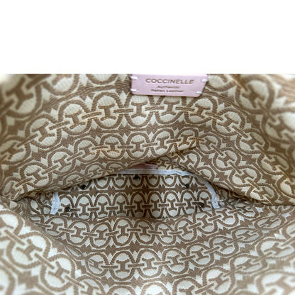 Interno di una borsa Coccinelle in pelle color cammello con parti metalliche argentate e interno in tessuto logato; munita di un manico singolo leggermente regolabile. Indossabile a spalla.