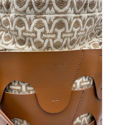 Logo di una borsa Coccinelle in pelle color cammello con parti metalliche argentate e interno in tessuto logato; munita di un manico singolo leggermente regolabile. Indossabile a spalla.