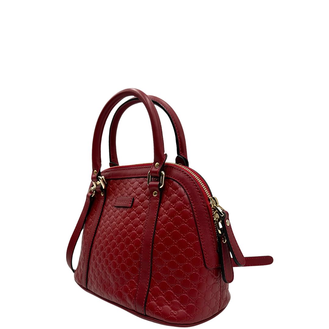 Laterale destro di una tracolla Gucci Microguccissima in color rosso ciliegia, con metalleria dorata, usata, originale, second hand, in ottime condizioni.