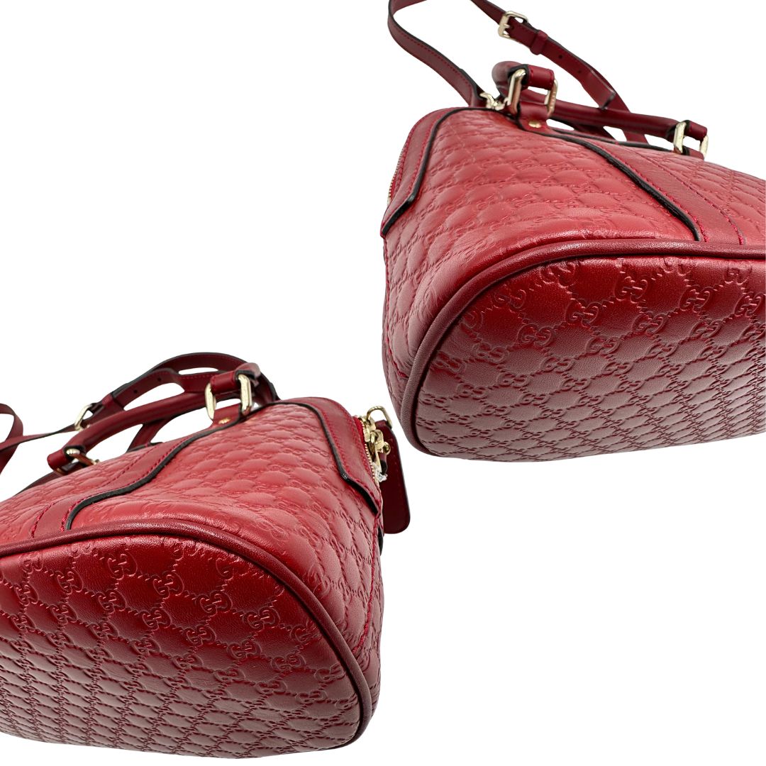 Angoli di una tracolla Gucci Microguccissima in color rosso ciliegia, con metalleria dorata, usata, originale, second hand, in ottime condizioni.