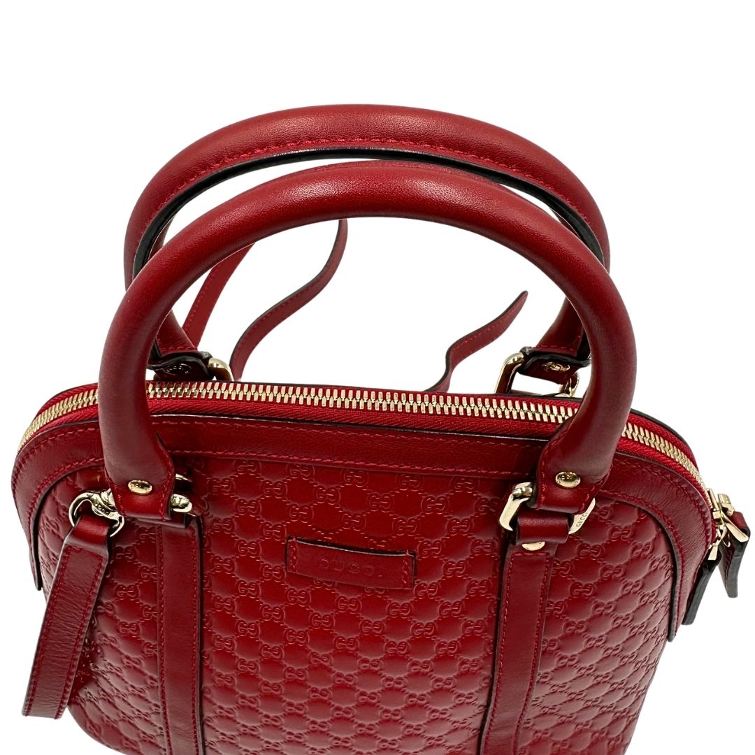 Manici di una tracolla Gucci Microguccissima in color rosso ciliegia, con metalleria dorata, usata, originale, second hand, in ottime condizioni.