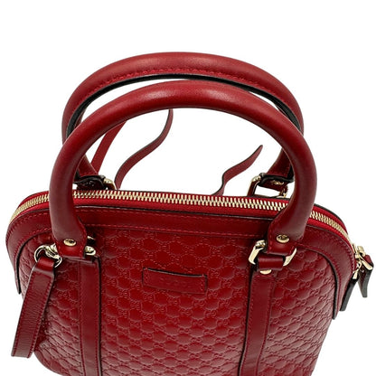 Manici di una tracolla Gucci Microguccissima in color rosso ciliegia, con metalleria dorata, usata, originale, second hand, in ottime condizioni.