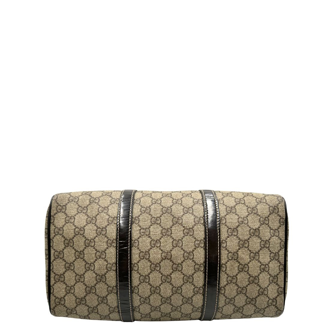 Base di un bauletto Gucci Supreme in canvas beige e dettagli in pelle marroni.