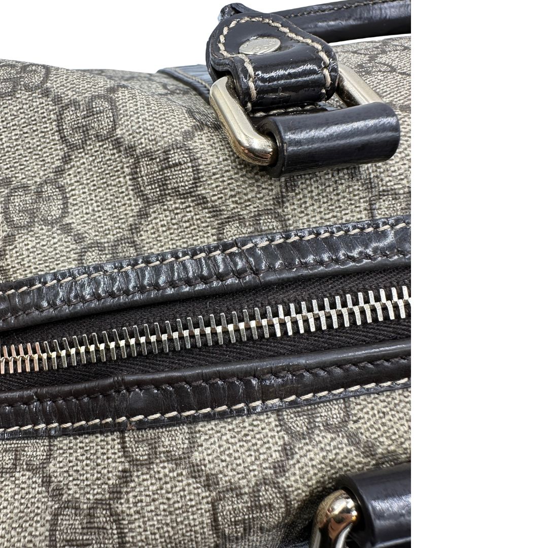 Difetti sulla pelle di un bauletto Gucci Supreme in canvas beige e dettagli in pelle marroni.