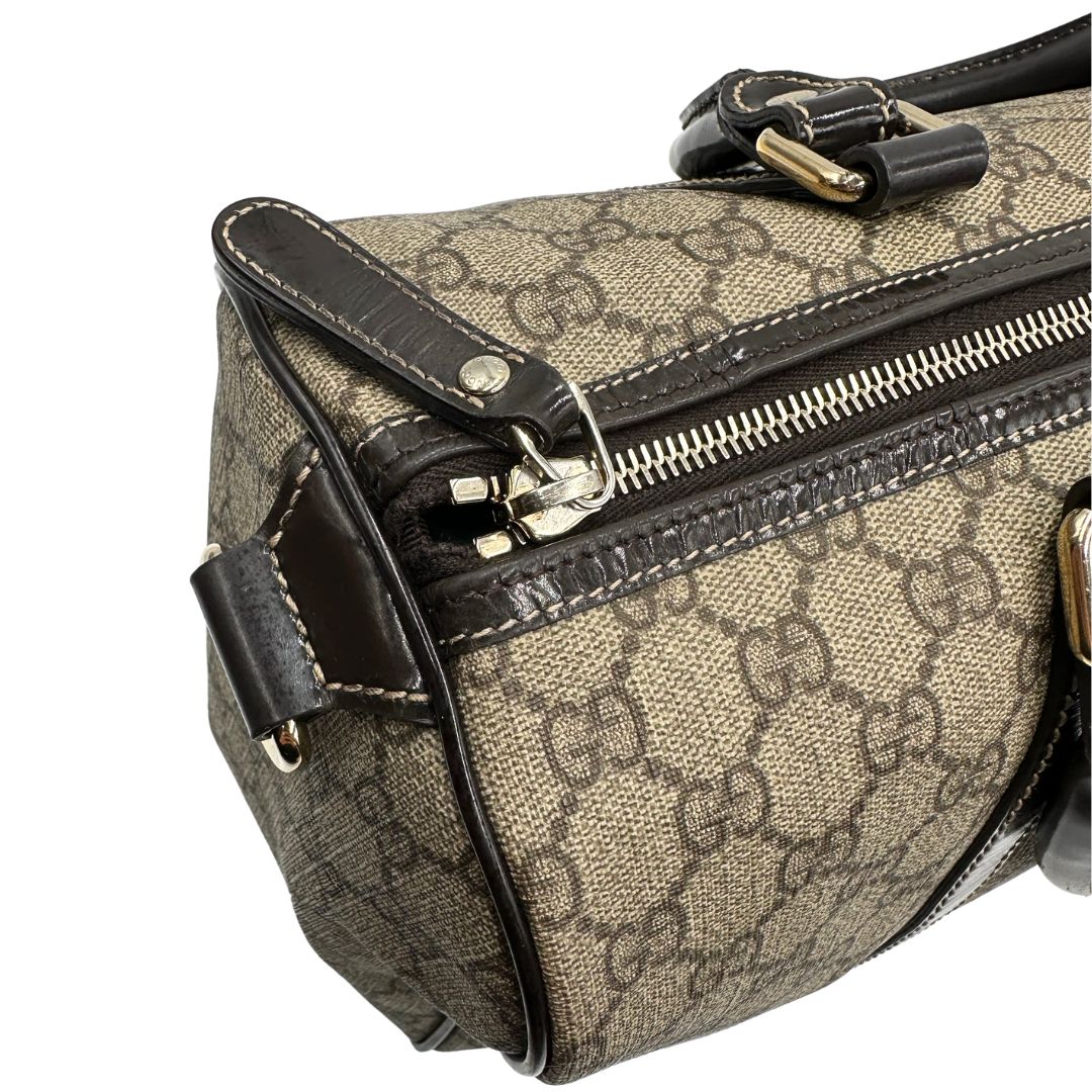 Chiusura di un bauletto Gucci Supreme in canvas beige e dettagli in pelle marroni.