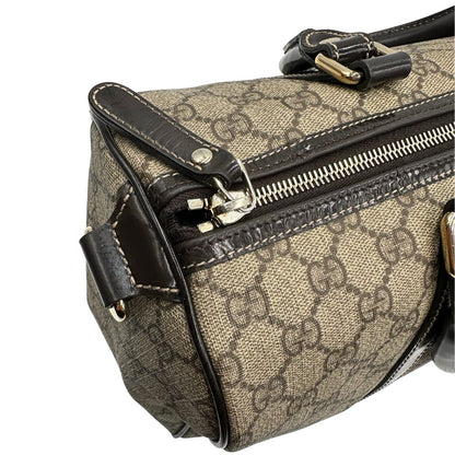 Chiusura di un bauletto Gucci Supreme in canvas beige e dettagli in pelle marroni.