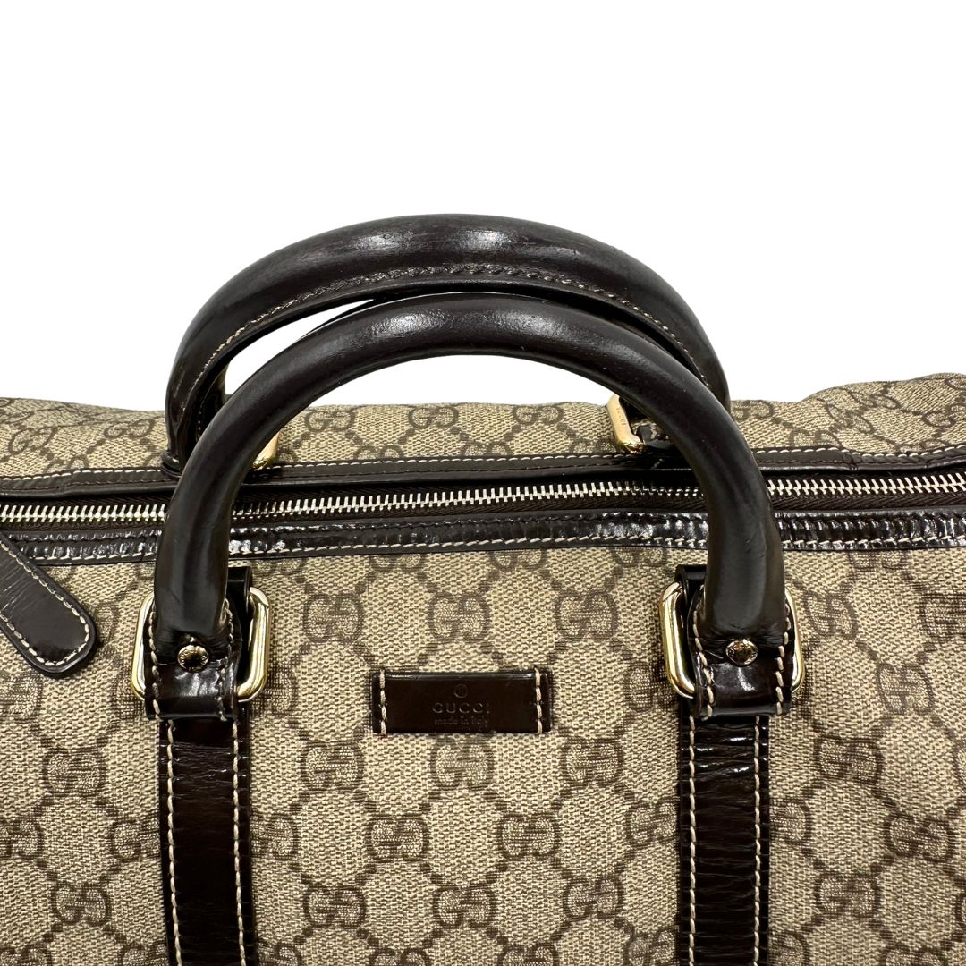 Manici di un bauletto Gucci Supreme in canvas beige e dettagli in pelle marroni.