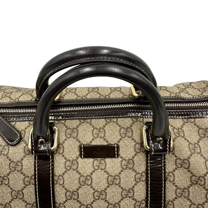 Manici di un bauletto Gucci Supreme in canvas beige e dettagli in pelle marroni.