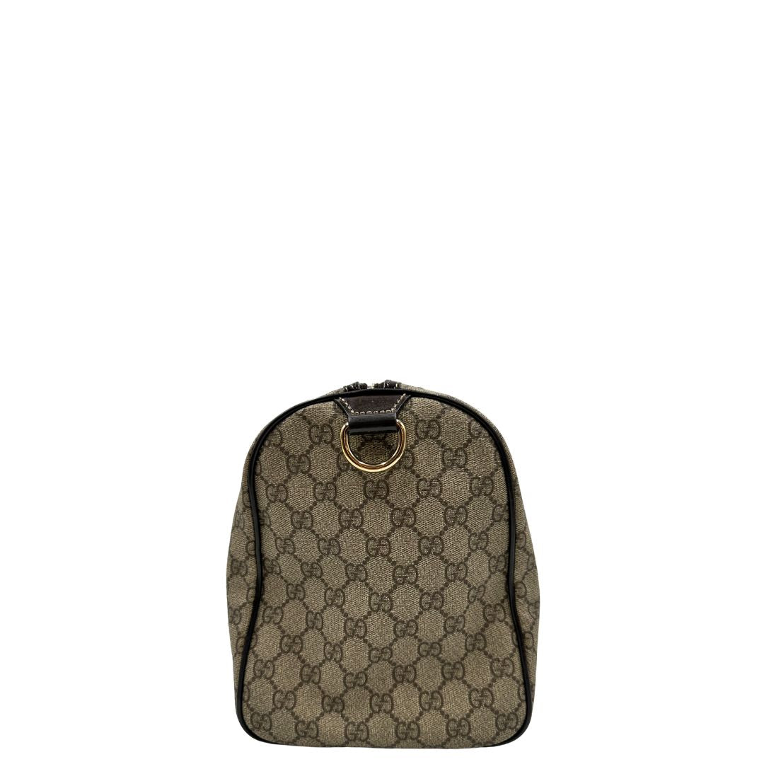 Vista laterale di un bauletto Gucci Supreme in canvas beige e dettagli in pelle marroni.