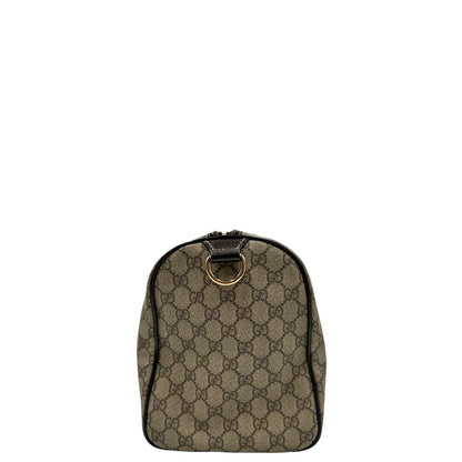 Vista laterale di un bauletto Gucci Supreme in canvas beige e dettagli in pelle marroni.