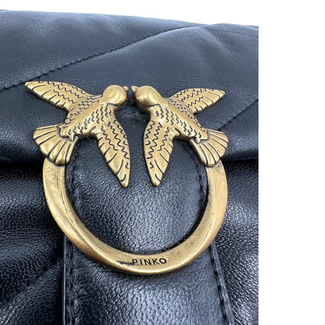 Logo segnato di una Pinko in pelle nera trapuntata, indossabile a spalla o a tracolla, usata, originale, second hand, in ottime condizioni.