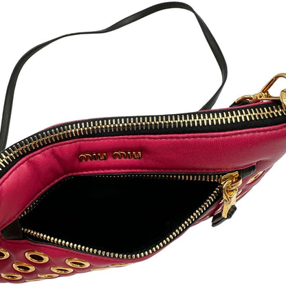 Apertura di una pochette con tracolla Miu Miu Biker in morbida nappa vele color azalea e hardware dorato, caratterizzata da occhielli metallici, usata, originale, second hand, in ottime condizioni.