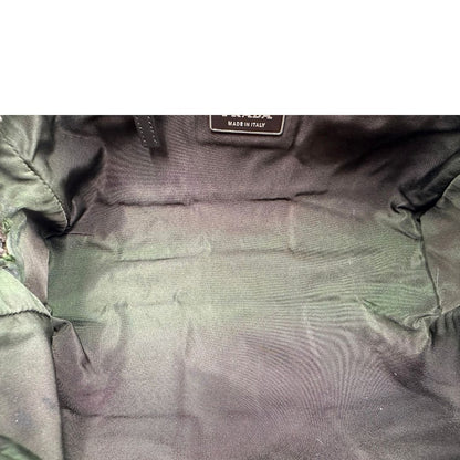 Interno di un bauletto Prada in tessuto nylon verde militare e pelle marrone, con dettagli metallici argentati, indossabile a mano.