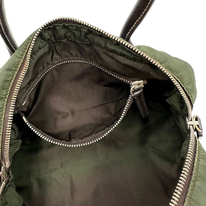 Interno di un bauletto Prada in tessuto nylon verde militare e pelle marrone, con dettagli metallici argentati, indossabile a mano.