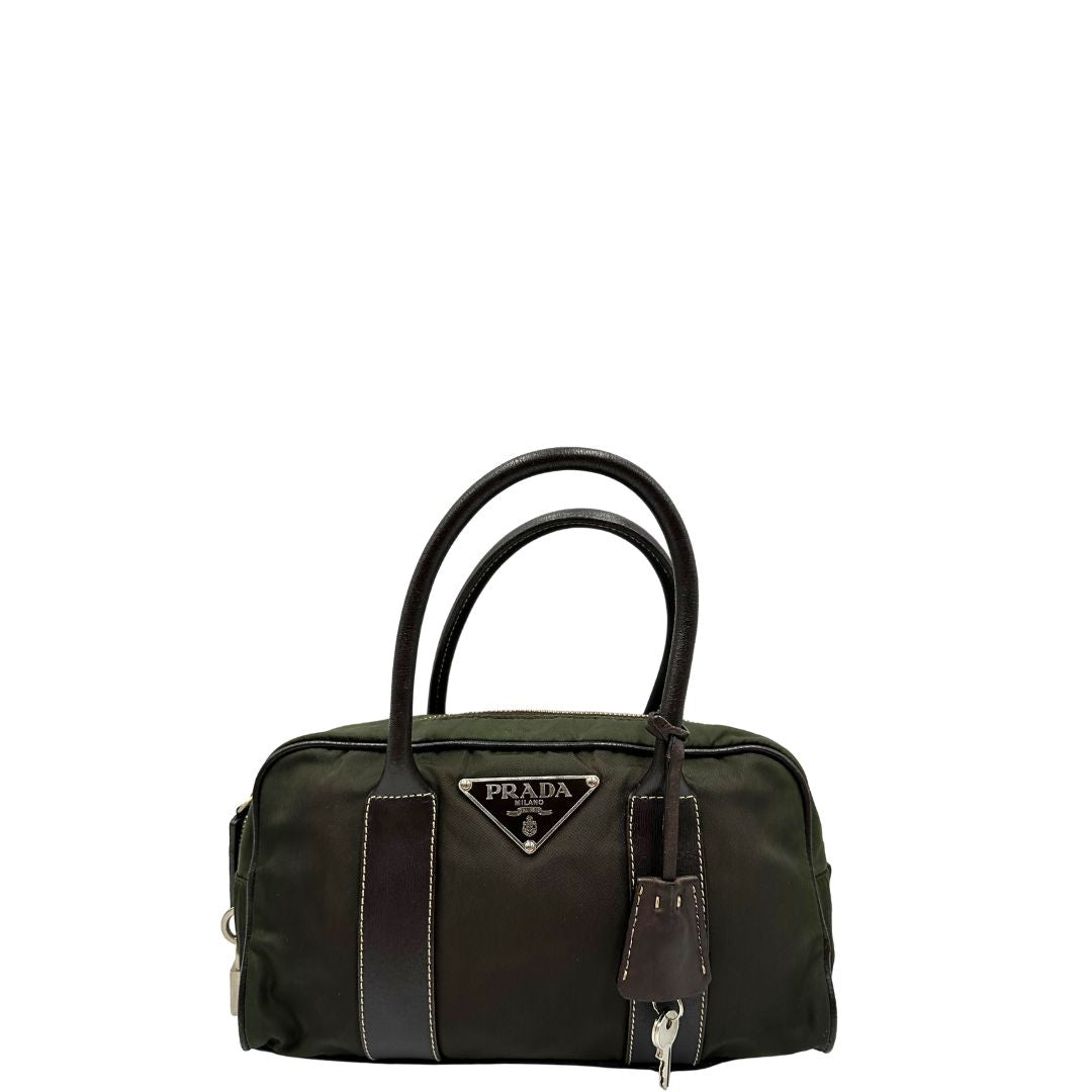 Front di un bauletto Prada in tessuto nylon verde militare e pelle marrone, con dettagli metallici argentati, indossabile a mano.