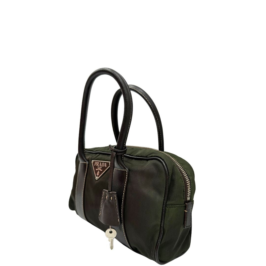 Laterale destro di un bauletto Prada in tessuto nylon verde militare e pelle marrone, con dettagli metallici argentati, indossabile a mano.
