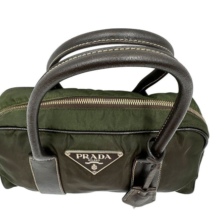 Manici di un bauletto Prada in tessuto nylon verde militare e pelle marrone, con dettagli metallici argentati, indossabile a mano.