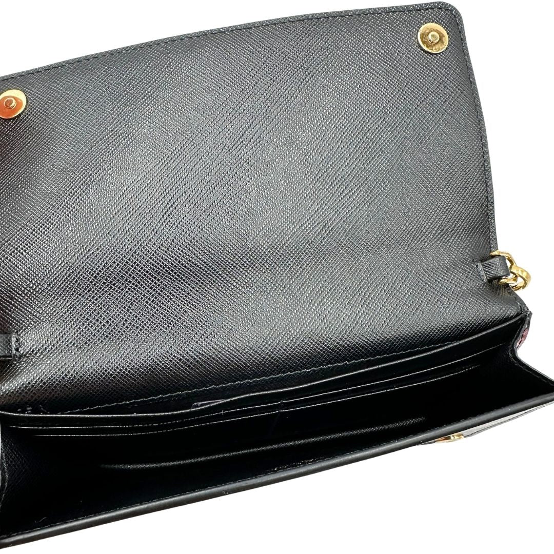 Interno di un Prada WOC in pelle saffiano nera, decorato con una vivace stampa di rossetti. Indossabile a tracolla oppure a mano, usato, originale, second hand, in ottime condizioni.