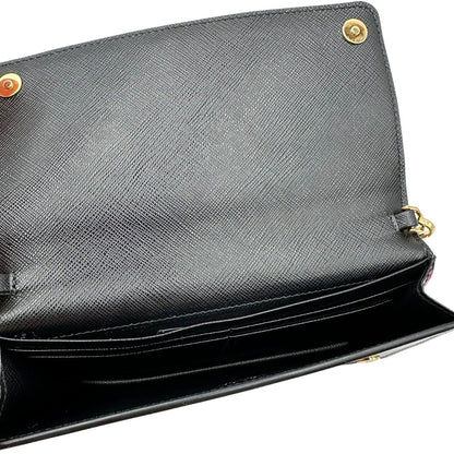 Interno di un Prada WOC in pelle saffiano nera, decorato con una vivace stampa di rossetti. Indossabile a tracolla oppure a mano, usato, originale, second hand, in ottime condizioni.