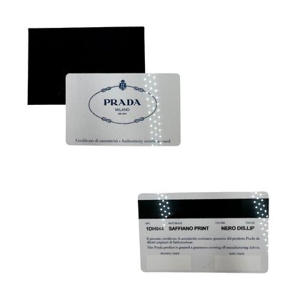 Card d'autenticità di un Prada WOC in pelle saffiano nera, decorato con una vivace stampa di rossetti. Indossabile a tracolla oppure a mano, usato, originale, second hand, in ottime condizioni.
