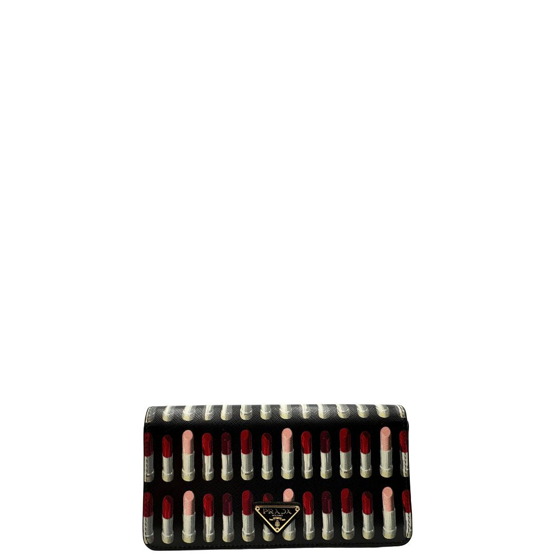 Front di un Prada WOC in pelle saffiano nera, decorato con una vivace stampa di rossetti. Indossabile a tracolla oppure a mano, usato, originale, second hand, in ottime condizioni.