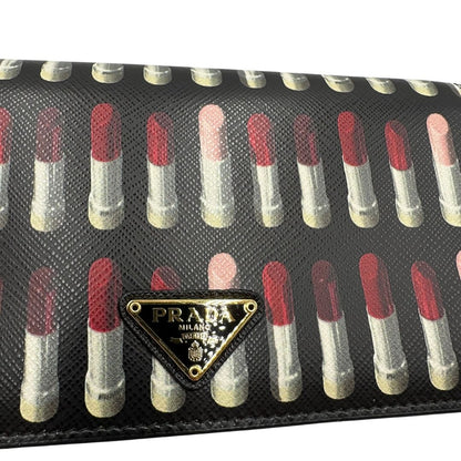 Logo di un Prada WOC in pelle saffiano nera, decorato con una vivace stampa di rossetti. Indossabile a tracolla oppure a mano, usato, originale, second hand, in ottime condizioni.
