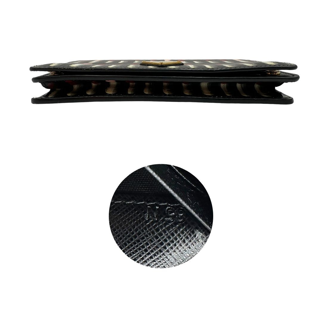 Base e codice di un Prada WOC in pelle saffiano nera, decorato con una vivace stampa di rossetti. Indossabile a tracolla oppure a mano, usato, originale, second hand, in ottime condizioni.