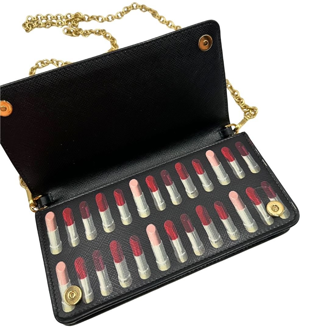 Apertura di un Prada WOC in pelle saffiano nera, decorato con una vivace stampa di rossetti. Indossabile a tracolla oppure a mano, usato, originale, second hand, in ottime condizioni.