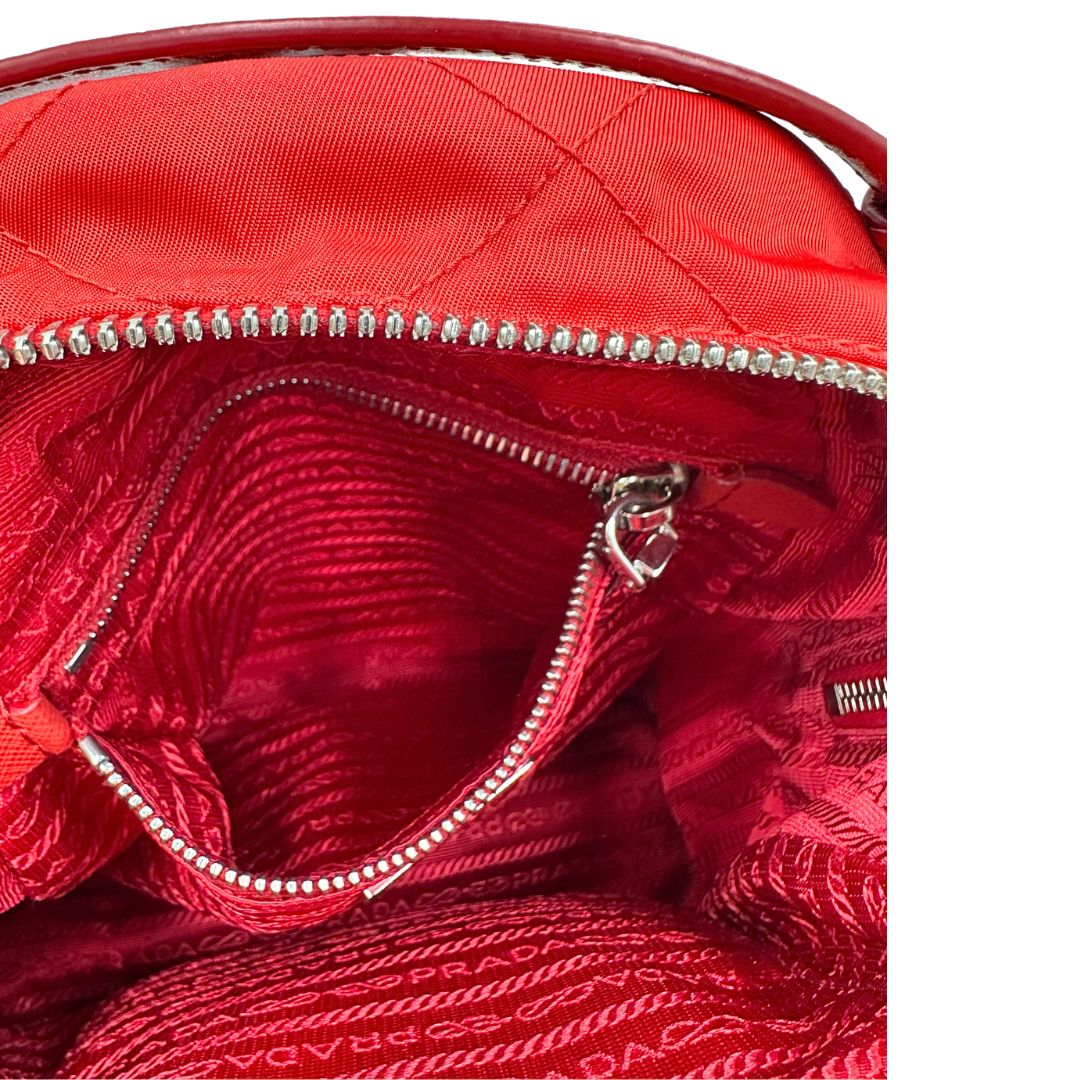 Interno di uno zaino Prada in tessuto sintetico rosso e finiture in pelle tono su tono, usato, originale, second hand, in ottime condizioni.