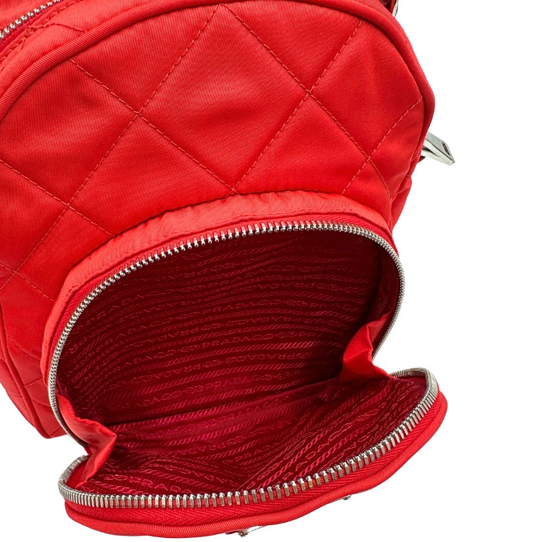 Interno del taschino frontale di uno zaino Prada in tessuto sintetico rosso e finiture in pelle tono su tono, usato, originale, second hand, in ottime condizioni.