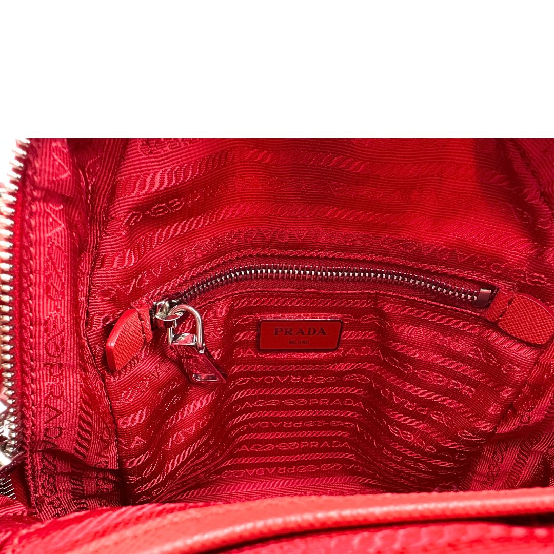 Interno di uno zaino Prada in tessuto sintetico rosso e finiture in pelle tono su tono, usato, originale, second hand, in ottime condizioni.