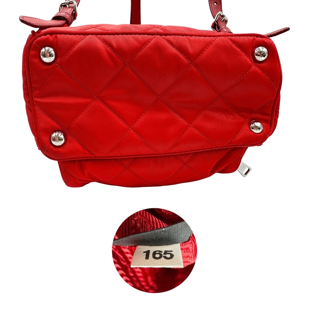 Base e codice di uno zaino Prada in tessuto sintetico rosso e finiture in pelle tono su tono, usato, originale, second hand, in ottime condizioni.
