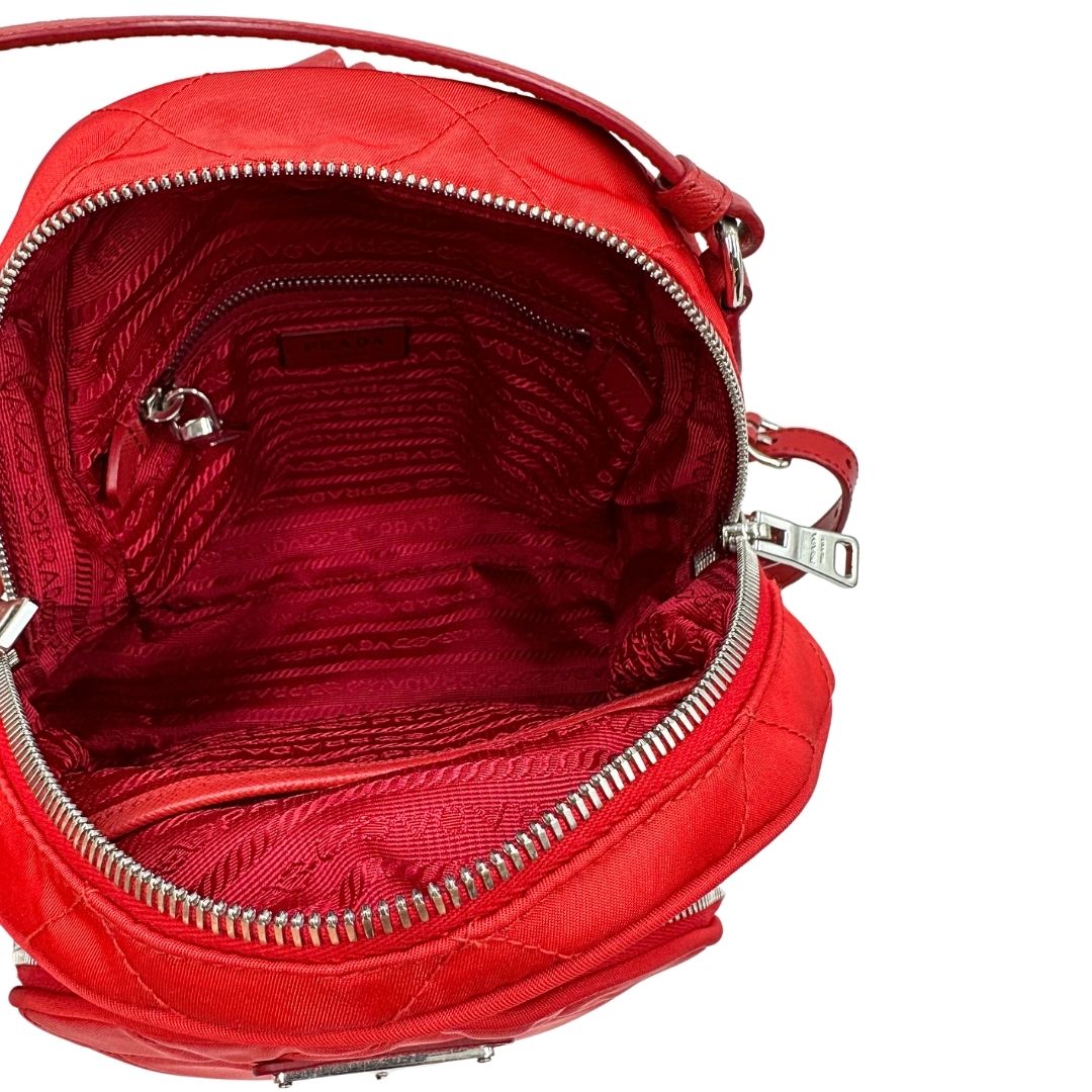 Interno di uno zaino Prada in tessuto sintetico rosso e finiture in pelle tono su tono, usato, originale, second hand, in ottime condizioni.