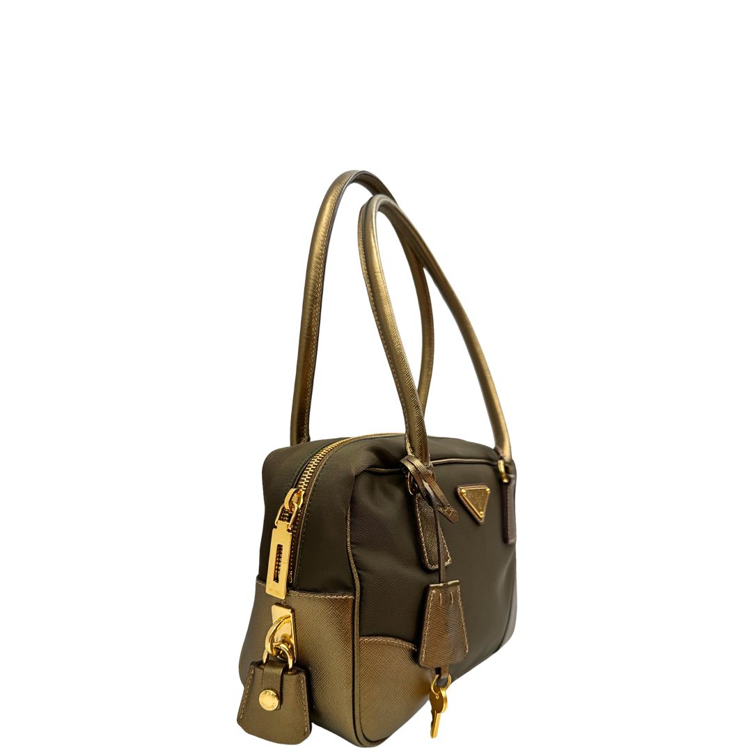 Laterale sinistro di un bauletto Prada in tessuto nylon e pelle saffiano bronzo, con dettagli metallici dorati, indossabile a spalla, usato, originale, second hand, in ottime condizioni.
