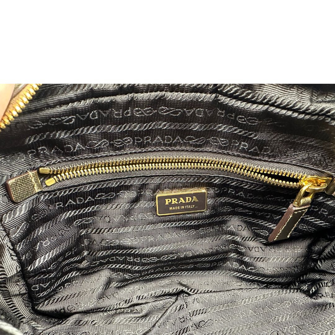 Interno di un bauletto Prada in tessuto nylon e pelle saffiano bronzo, con dettagli metallici dorati, indossabile a spalla, usato, originale, second hand, in ottime condizioni.